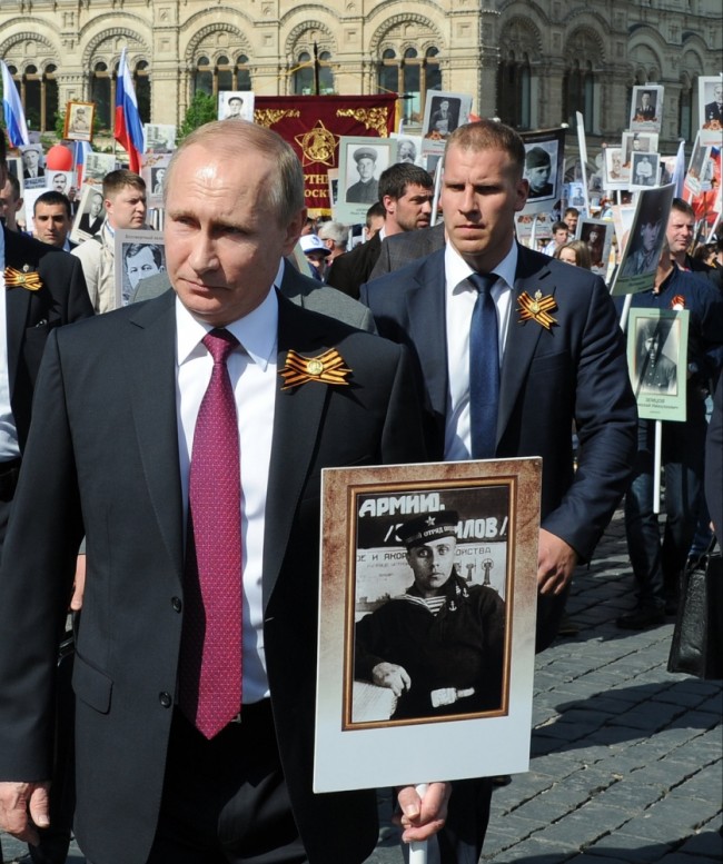 Russian President Vladimir Putin, center, holds a photograph of his father in a naval uniform, as he walks with people carrying portraits of relatives who fought in World War II, during the Immortal Regiment march in Red Square, in Moscow, Russia, Monday, May 9, 2016. The march of the so-called Immortal Regiment is part of commemoration of the 71st anniversary of the victory in WWII. (Mikhail Klimentyev/Sputnik, Kremlin Pool Photo via AP)