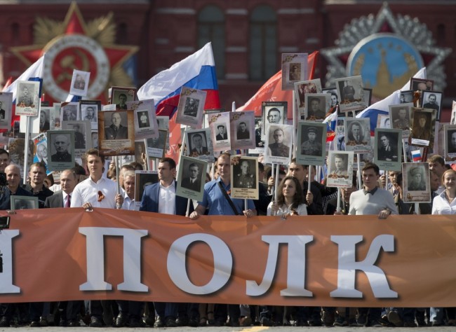 Russian President Vladimir Putin, third left, walks with people carrying portraits of relatives who fought in World War II, during the Immortal Regiment march in Red Square, in Moscow, Russia, Monday, May 9, 2016. The march of the so-called Immortal Regiment is part of commemoration of the 71st anniversary of the victory in WWII. A poster reads Immortal Regiment. (AP Photo/Alexander Zemlianichenko)