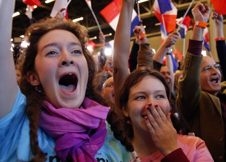 Supporters of French centrist presidential candidate Emmanuel Macron react at his election day headquarters as the first partial official results and polling agencies projections are announced in Paris , Sunday April 23, 2017. Pollsters projected that pro-Europe centrist Emmanuel Macron and far-right populist Marine Le Pen both advanced Sunday from the first round of voting in France's presidential election. (AP Photo/Christophe Ena)