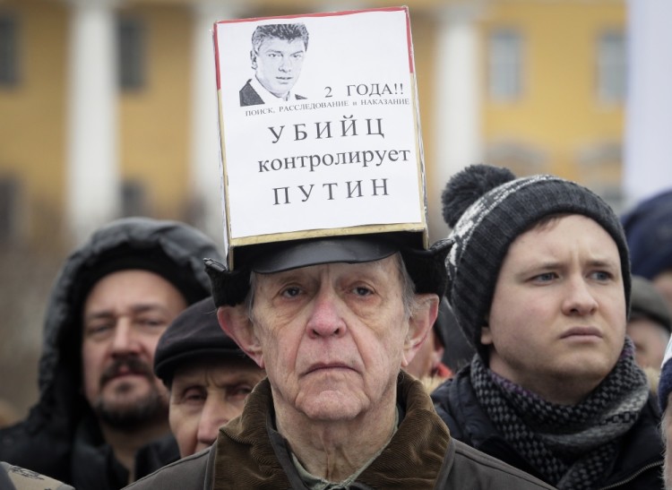 A man displays a poster reading 'Putin controls murderers' during a rally in memory of opposition leader Boris Nemtsov in St.Petersburg, Russia, Sunday, Feb. 26, 2017. Thousands of Russians have taken to the streets of downtown Moscow and St.Petersburg to mark two years since Nemtsov was gunned down outside the Kremlin. (AP Photo/Dmitri Lovetsky)