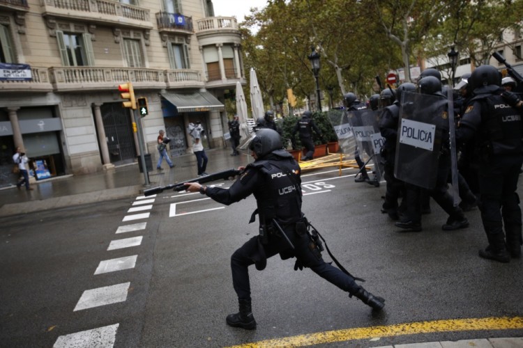 Spanish riot police shoots rubber bullet straight to people trying to reach a voting site at a school assigned to be a polling station by the Catalan government in Barcelona, Spain, Sunday, 1 Oct. 2017. Spanish riot police have forcefully removed a few hundred would-be voters from several polling stations in Barcelona. (AP Photo/Emilio Morenatti)