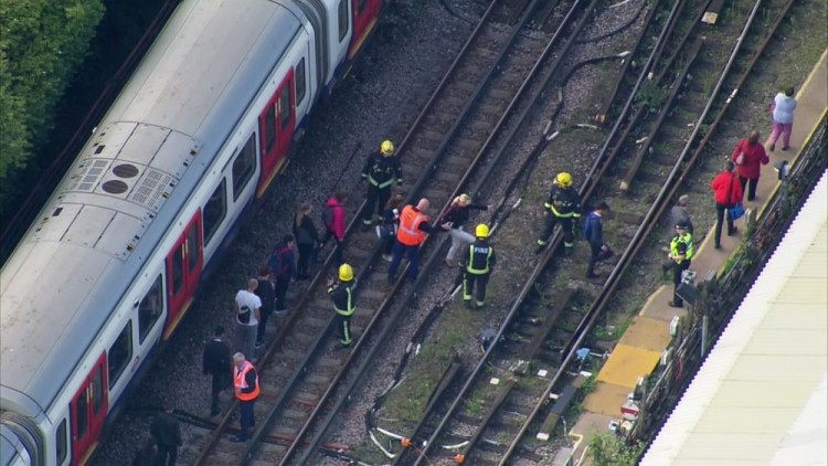 In this aerial image made from video, emergency workers help people to disembark a train near the Parsons Green Underground Station after an explosion in London Friday, Sept. 15, 2017. A reported explosion at a train station sent commuters stampeding in panic, injuring several people at the height of London's morning rush hour, and police said they were investigating it as a terrorist attack. (Pool via AP)