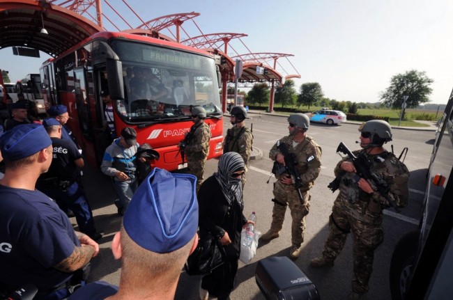 Венгерские военнослужащие и полиция обеспечивают порядок при посадке беженцев в автобусы на границе с Хорватией. Фото AFP/Scanpix