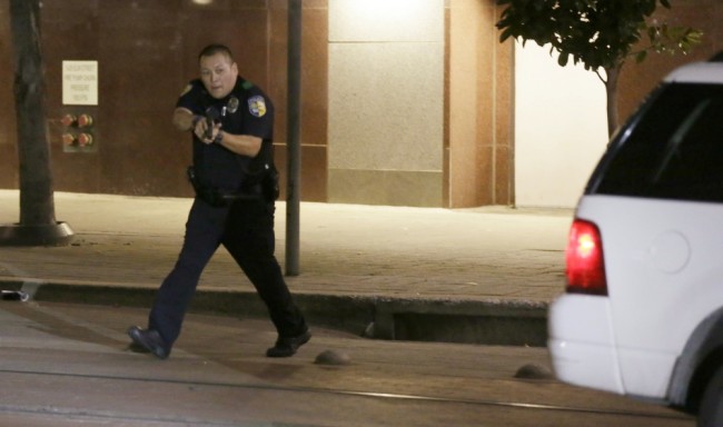 Dallas police move to detains a driver after several police officers were shot in downtown Dallas, Thursday, July 7, 2016. Snipers apparently shot police officers during protests and some of the officers are dead, the city's police chief said in a statement. (AP Photo/LM Otero)