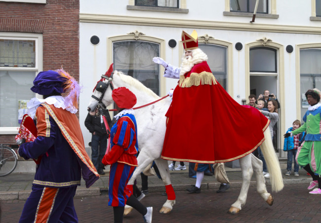 DORDRECHT, NETHERLANDS - NOVEMBER 17: Saint Nicholas on his white horse riding through the streets of Dordrecht with zwarte Piet as escort waving to the children on November 17, 2012 in Dordrecht, Netherlands.