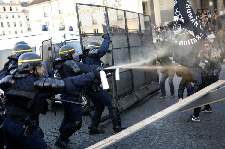 Police officers spray gas on demonstrators during a protest in Paris , Sunday April 23, 2017. Protesters angry that far-right leader Marine Le Pen is advancing the French presidential runoff are scuffling with police in Paris. (AP Photo/Kamil Zihnioglu)