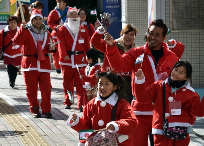 Зрители одетые в  костюмы Санта-Клауса приветствуют участников 