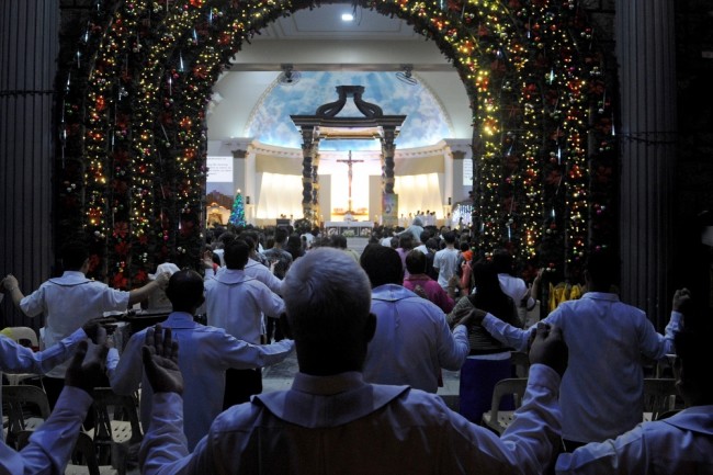 TOPSHOT - Colourful lights outline the doorway of the Roman Catholic Church as Filipinos attend the first of nine dawn masses signalling the official start of the Christmas season in suburban Manila on December 16, 2015. The tradition of dawn masses dates back to the Spanish era. It culminates on Christmas Eve and it is a belief that anyone who completes the chain will have his wish granted.   AFP PHOTO / Jay DIRECTO / AFP / JAY DIRECTO