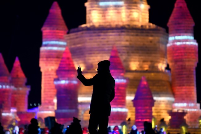 A man takes a photo in front of ice sculptures at the China Ice and Snow World on eve of the opening ceremony of the Harbin International Ice and Snow Festival in Harbin, northeast China's Heilongjiang province on January 4, 2016. Over one million visitors are expected to attend the spectacular Harbin Ice Festival, where buildings of ice are bathed in ethereal lights and international ice sculptors compete for honours.     AFP PHOTO / WANG ZHAO