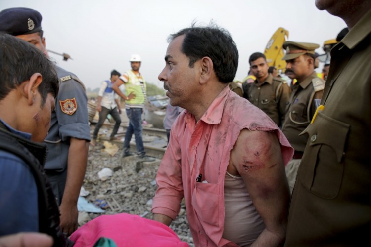 An injured survivor looks for a missing member of his team after 14 coaches of an overnight passenger train rolled off the track near Pukhrayan village Kanpur Dehat district, Uttar Pradesh state, India, Sunday, Nov. 20, 2016. Dozens were killed and dozens more were injured in the accident. (AP Photo/Rajesh Kumar Singh)