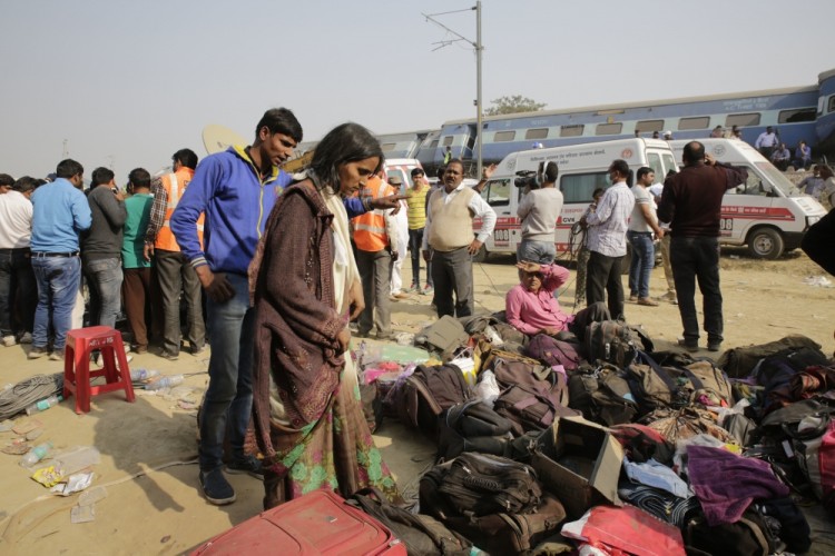 People stand near the belongings of passengers after 14 coaches of an overnight passenger train rolled off the track near Pukhrayan village Kanpur Dehat district, Uttar Pradesh state, India, Sunday, Nov. 20, 2016. Dozens were killed and dozens more were injured in the accident. (AP Photo/Rajesh Kumar Singh)