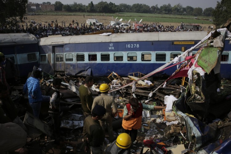 Rescuers stand amid debris after 14 coaches of an overnight passenger train rolled off the track near Pukhrayan village Kanpur Dehat district, Uttar Pradesh state, India, Sunday, Nov. 20, 2016. Dozens were killed and dozens more were injured in the accident. (AP Photo/Rajesh Kumar Singh)