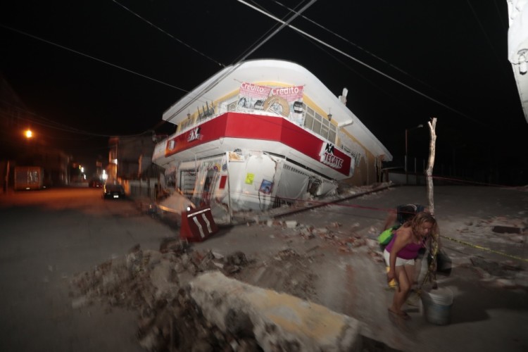 A woman walks past a collapsed building after a 7.1 earthquake, in Jojutla, Morelos state, Mexico, Tuesday, Sept. 19, 2017. The earthquake stunned central Mexico, killing more than 100 people as buildings collapsed in plumes of dust. (AP Photo/Eduardo Verdugo)