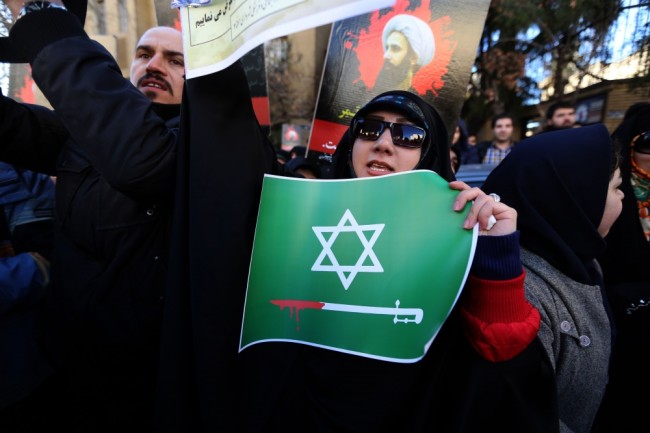 Участница акции протеста в Иране перед зданием посольства Саудовской Аравии с плакатом. Фото AFP/Scanpiх
