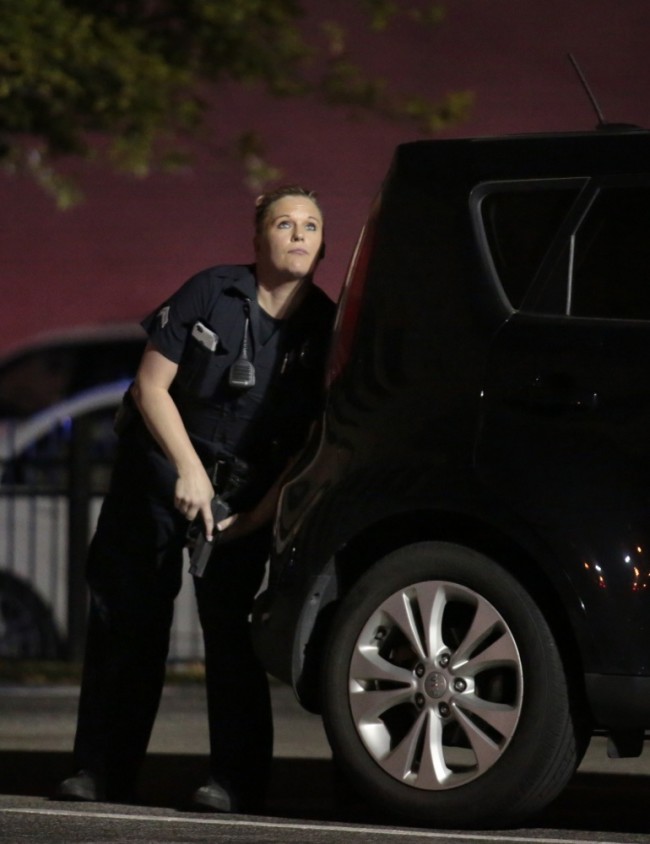A police officer looks up while standing behind a vehicle, as police responded to shots being fired during a protest over recent fatal shootings by police in Louisiana and Minnesota, Thursday, July 7, 2016, in Dallas. Snipers opened fire on police officers during protests; several officers were killed, police said. (Maria R. Olivas/The Dallas Morning News via AP)