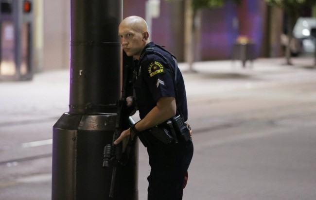 A Dallas policeman keeps watch on a street in downtown Dallas, Thursday, July 7, 2016, following reports that shots were fired during a protest over two recent fatal police shootings of black men. (AP Photo/LM Otero)