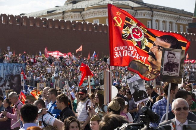 People carry portraits of relatives who fought in World War II, and a flag with a portrait of Soviet dictator Josef Stalin and a sign reading 