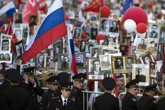 People carry portraits of relatives who fought in World War II, and Russian and Soviet flags, during the Immortal Regiment march in Moscow, Russia, Monday, May 9, 2016. The march of the so-called Immortal Regiment is part of commemoration of the 71st anniversary of the victory in WWII. (AP Photo/Pavel Golovkin)
