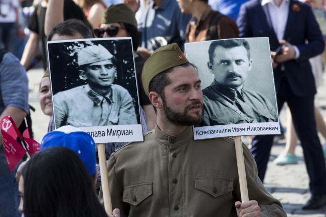 A man, dressed in WWII era Soviet uniform, carries two portraits during the Immortal Regiment march in Red Square, in Moscow, Russia, Monday, May 9, 2016. The march of the so-called Immortal Regiment when people carry portraits of relatives who fought in World War II,  is part of commemoration of the 71st anniversary of the victory in WWII. (AP Photo/Alexander Zemlianichenko)