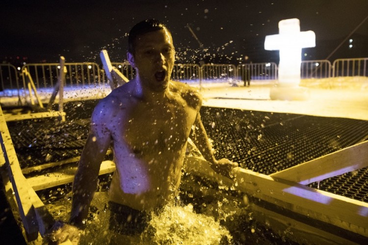 A Russian man bathes in the icy water to mark the Epiphany in Moscow, Russia, Wednesday, Jan. 18, 2017, with the temperature in Moscow at about -6 C (21 F). Thousands of Russian Orthodox Church followers plunged into icy rivers and ponds across the country to mark Epiphany, cleansing themselves with water deemed holy for the day.  (AP Photo/Pavel Golovkin)
