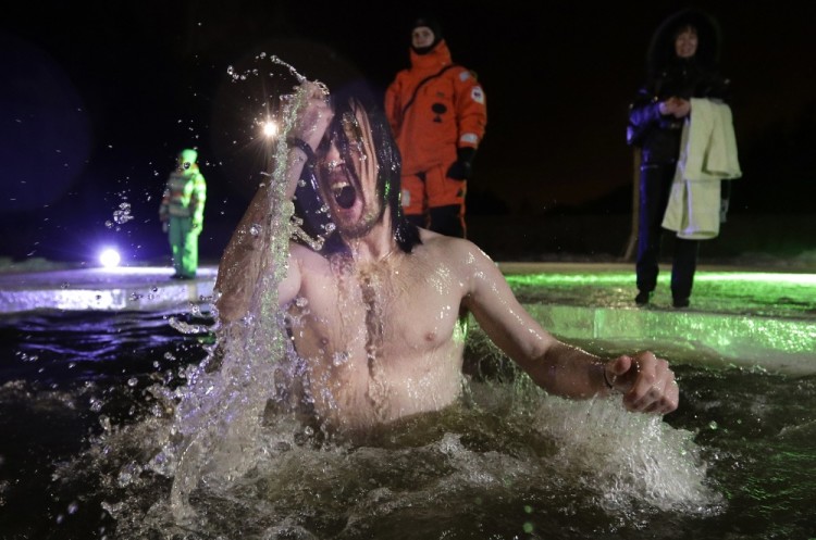 A Russian Orthodox believer swims in the icy water on Epiphany at a pond in Tyarlevo village outside St.Petersburg, Russia, late Wednesday, Jan. 18, 2017. The temperature in St. Petersburg is minus 2 degrees Centigrade (28 degrees Fahrenheit). Thousands of Russian Orthodox Church followers plunged into icy rivers and ponds across the country to mark Epiphany, cleansing themselves with water deemed holy for the day. Water that is blessed by a cleric on Epiphany is considered holy and pure until next year's celebration, and is believed to have special powers of protection and healing. (AP Photo/Dmitri Lovetsky)