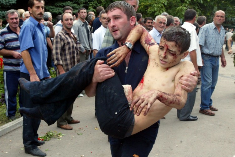 FILE - In this Friday, Sept. 3, 2004 file photo a wounded boy is carried after he escaped from a seized school in Beslan, Russia. The European Court of Human Rights said  Thursday, April 13, 2017, that Russia failed to adequately protect victims of a 2004 school siege in the city of Beslan that left more than 300 people dead. (AP Photo/Ivan Sekretarev, File)