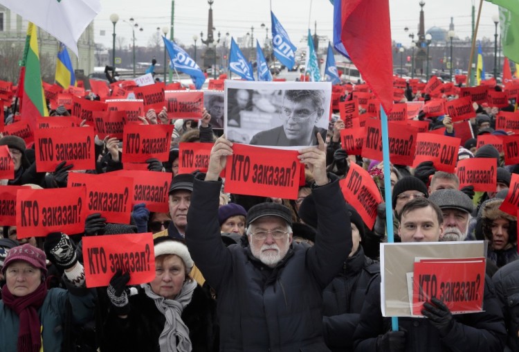 People hold posters reading 'Who ordered the murder?' during a rally in memory of opposition leader Boris Nemtsov in St. Petersburg, Russia, Sunday, Feb. 26, 2017. Thousands of Russians have taken to the streets of Moscow and St. Petersburg to mark two years since Nemtsov was gunned down outside the Kremlin. (AP Photo/Dmitri Lovetsky)