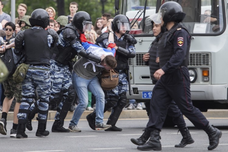 Special force policemen detain a protester covered with a Russian flag in Moscow, Russia, Monday, June 12, 2017.  Russian opposition leader Alexei Navalny, aiming to repeat the nationwide protests that rattled the Kremlin three months ago, has called for a last-minute location change for a Moscow demonstration. (AP Photo/Denis Tyrin)