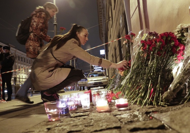 People lay flowers at a place near the Tekhnologichesky Institut subway station in St.Petersburg, Russia, Monday, April 3, 2017. A bomb blast tore through a subway train deep under Russia's second-largest city Monday, killing several people and wounding many more in a chaotic scene that left victims sprawled on a smoky platform. (AP Photo/Dmitri Lovetsky)