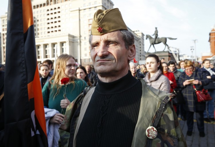 A man wearing a Soviet-era field cap, attends a rally honoring the victims of St. Petersburg's subway bombing just off Red Square in Moscow, Russia, Thursday, April 6, 2017. A bomb blast tore through a subway train under Russia's second-largest city on Monday, killing 14 people and wounding more than 40. In the background is a monument to Soviet Marshal Georgy Zhukov. (AP Photo/Alexander Zemlianichenko)