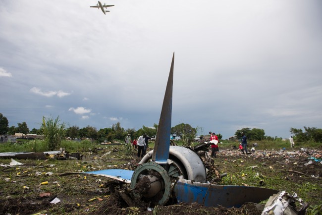 TOPSHOTS People gather at the site of a cargo plane crash, on a small island in the White Nile river, close to Juba airport, in the Hai Gabat residential area, on November 4, 2015. At least 27 people were killed today when a plane crashed shortly after taking off from South Sudan's capital Juba, an AFP reporter said. Police were pulling the bodies of men, women and children out of the wreckage of the Russian-built Antonov An-12 cargo plane, which smashed into a farming community on an island on the White Nile river, according to the reporter, who counted at least 27 dead.  AFP PHOTO / CHARLES LOMODONG