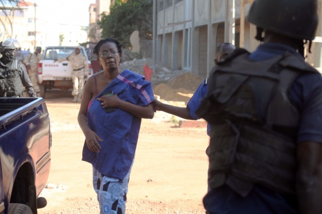 TOPSHOTS Malian security forces escort a hostage freed from the Radisson Blu hotel in Bamako on November 20, 2015. Gunmen went on a shooting rampage at the luxury hotel in Mali's capital Bamako, seizing 170 guests and staff in an ongoing hostage-taking that has left at least three people dead. AFP PHOTO / HABIBOU KOUYATE