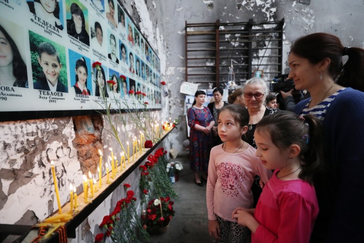 BESLAN, RUSSIA - SEPTEMBER 1, 2017: People look at photos of the victims of the 2004 Beslan school siege seen during a memorial event in the gym of School No 1. On September 1, 2004, a group of Chechen militants took more than 1,200 people hostage; the hostage crisis lasted for 3 days, leaving 334 people dead, including 186 children. Sergei Savostyanov/TASS