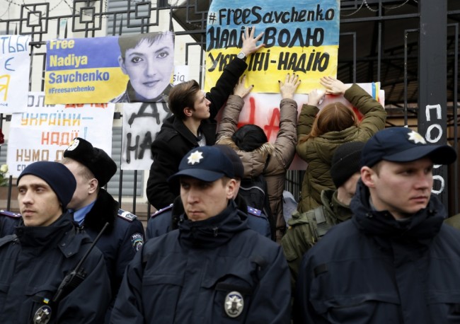 Activists hang posters on the fence of the Russian embassy in support of Ukrainian pilot Nadezhda Savchenko during a rally outside the Russian Embassy in Kiev, Ukraine, Wednesday, March 9 2016.  A Russian judge set a date of March 21-22 for issuing the verdict in the case against jailed Ukrainian pilot Nadezhda Savchenko, who is accused of involvement in the deaths of two Russian journalists during the conflict in eastern Ukraine. The judge said Wednesday, March 9, 2016, the reading of the verdict would begin March 21 and take two days. (AP Photo/Sergei Chuzavkov)